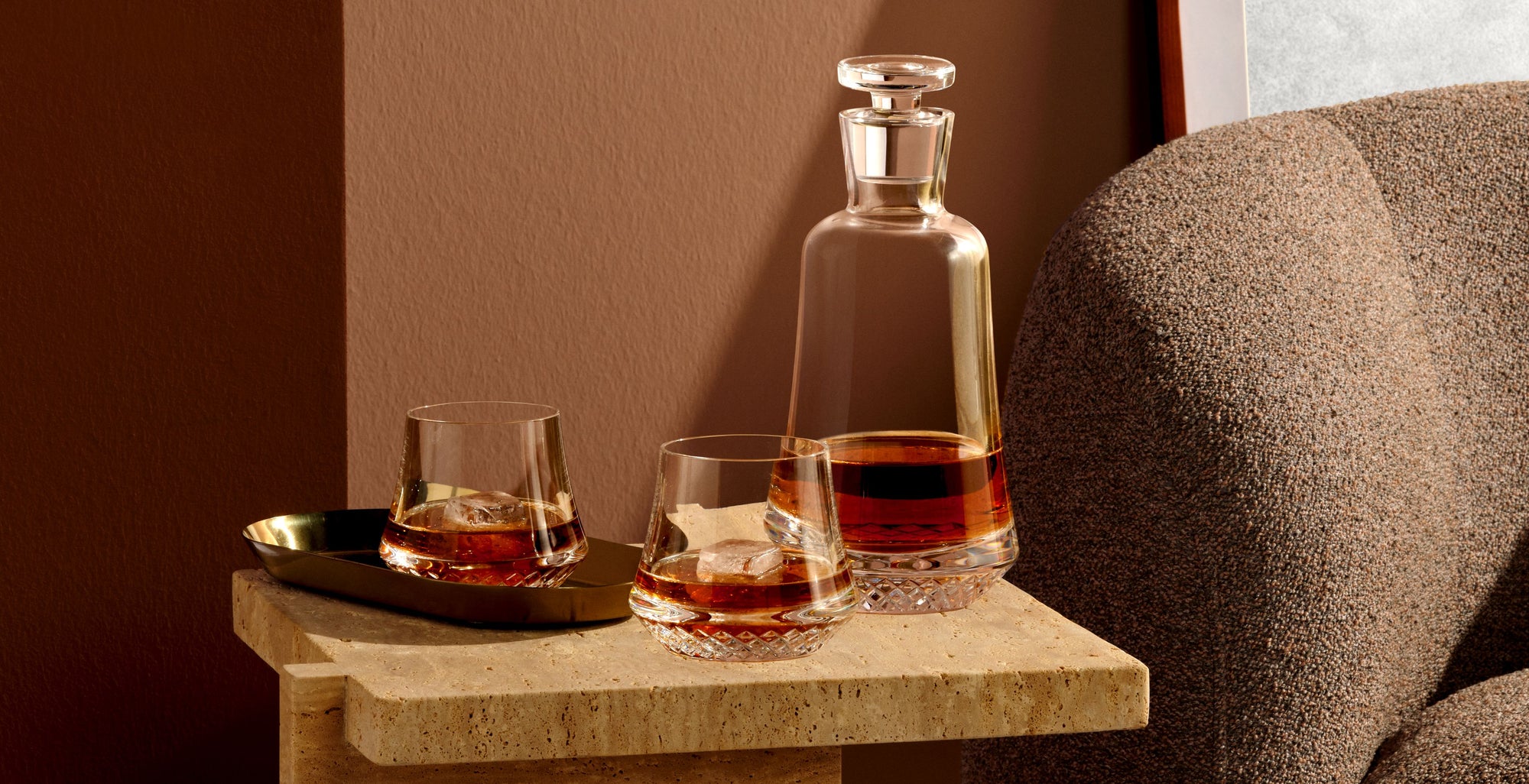 NUDE Paris Whisky bottle and glasses presented on a sidetable next to a sofa