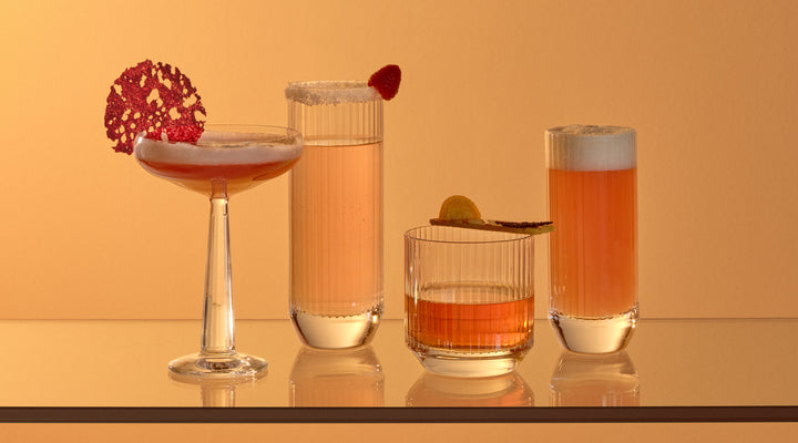 NUDE Big Top collection with coupe glass, dof whisky glass and highball glasses, presented in an orange sunset mood with orange toned cocktails