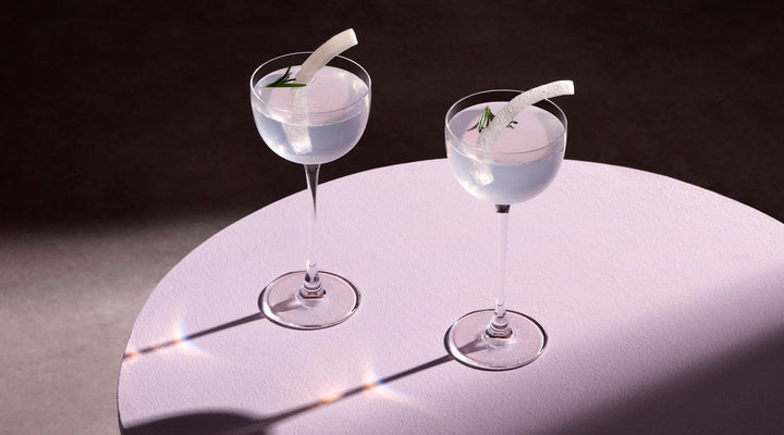 Set of 2 NUDE glass Savage pony glasses on a table with a play of their shadows on the table