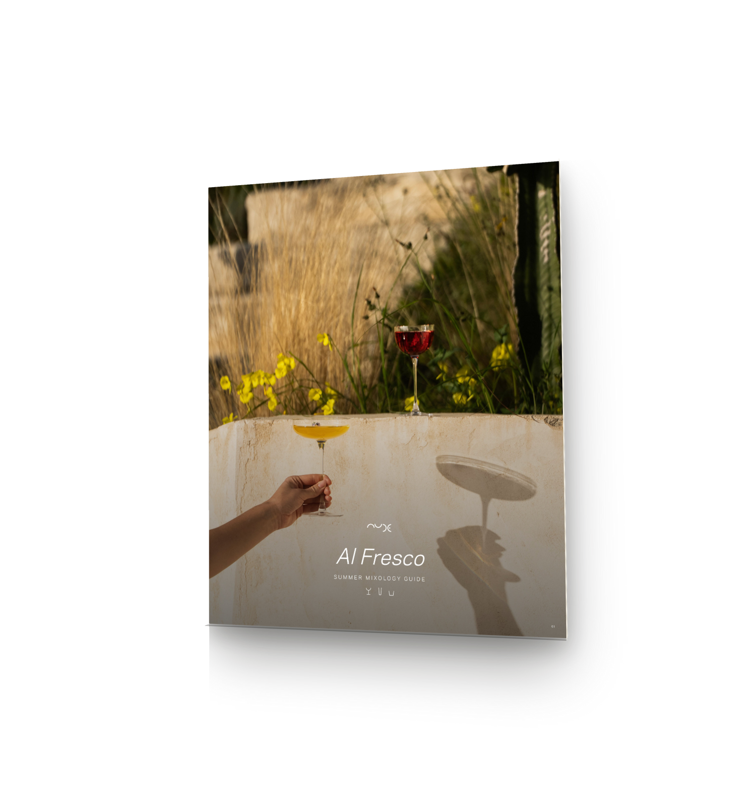 A tilted 3D mockup of the NUDE Summer Mixology Guide cover, showing a golden-hour photo of a Savage coupe glass and wine glass on a sunlit stone ledge, with the title "Al Fresco: Summer Mixology Guide" and three glass icons beneath it, angled to suggest a physical booklet with visible page edges.