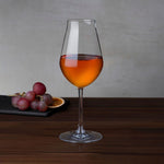 NUDE Salute sherry glass with amber wine beside red grapes and dried orange slice on a slate board