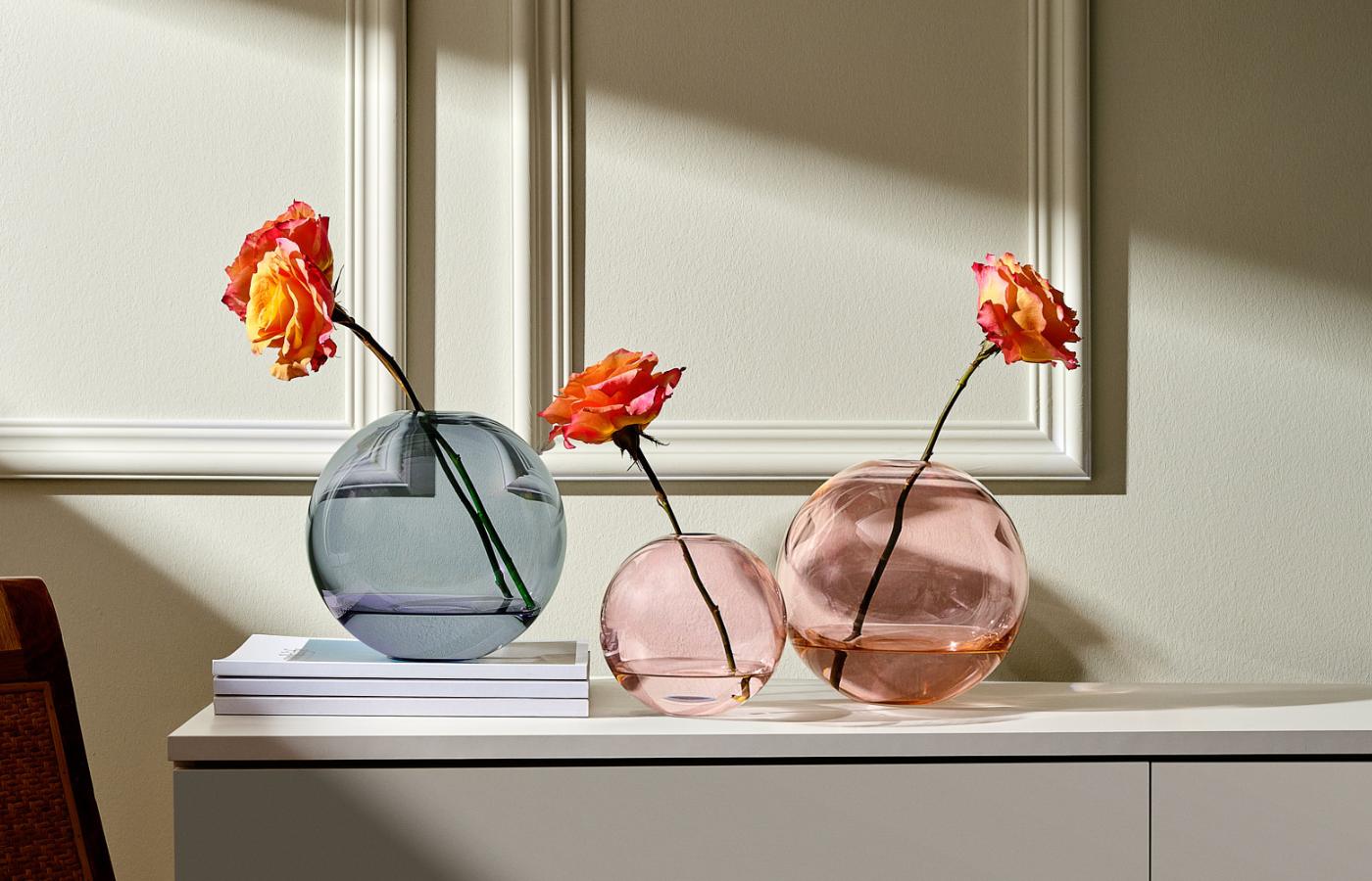 NUDE Mars Vases in steel blue and apricot holding single roses on a sideboard