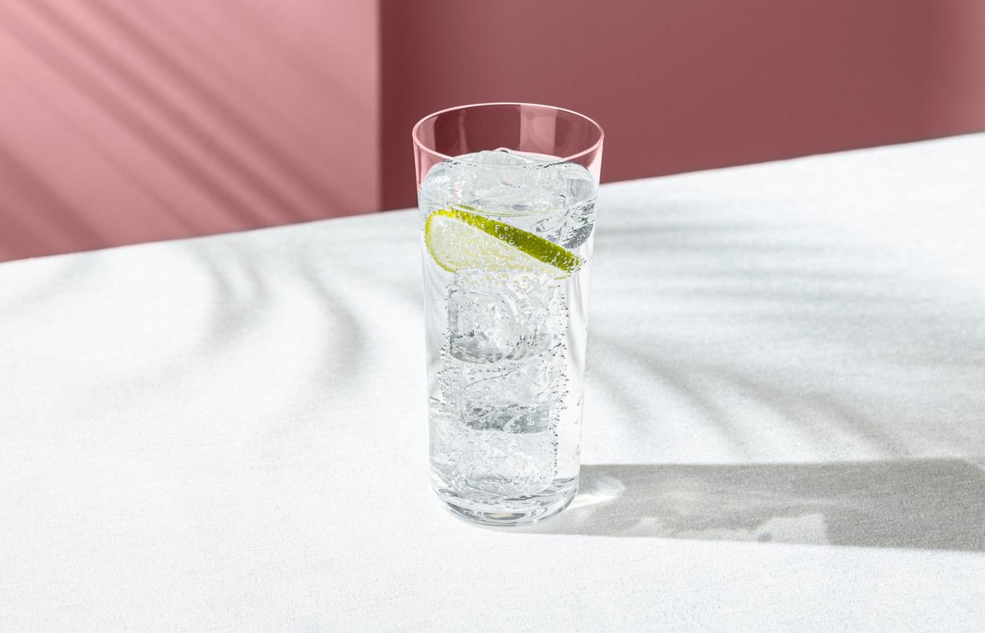  NUDE Savage High Ball Glass with a sparkling drink, ice and lime on a blush backdrop.