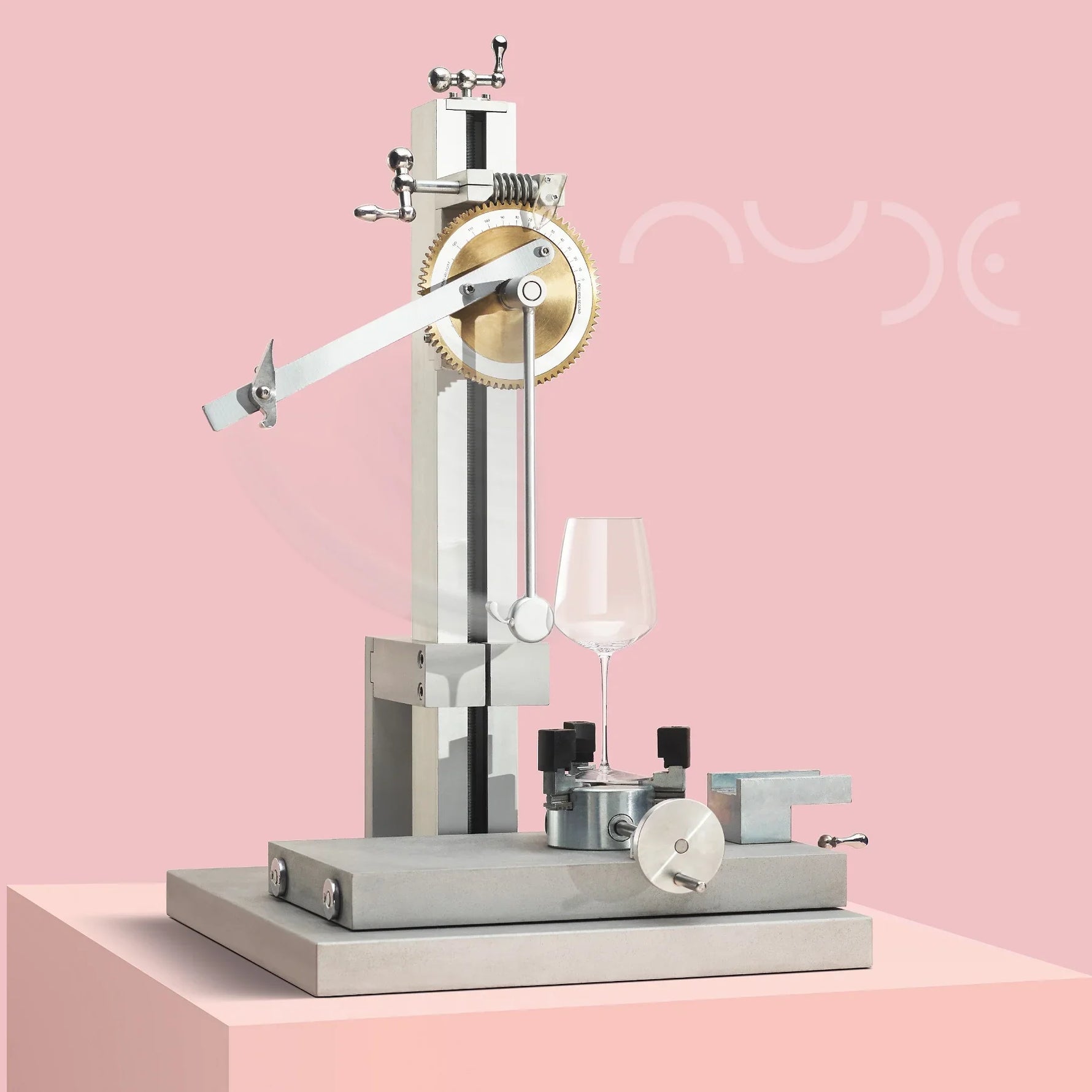 Mechanical device with a wine glass on a pink background