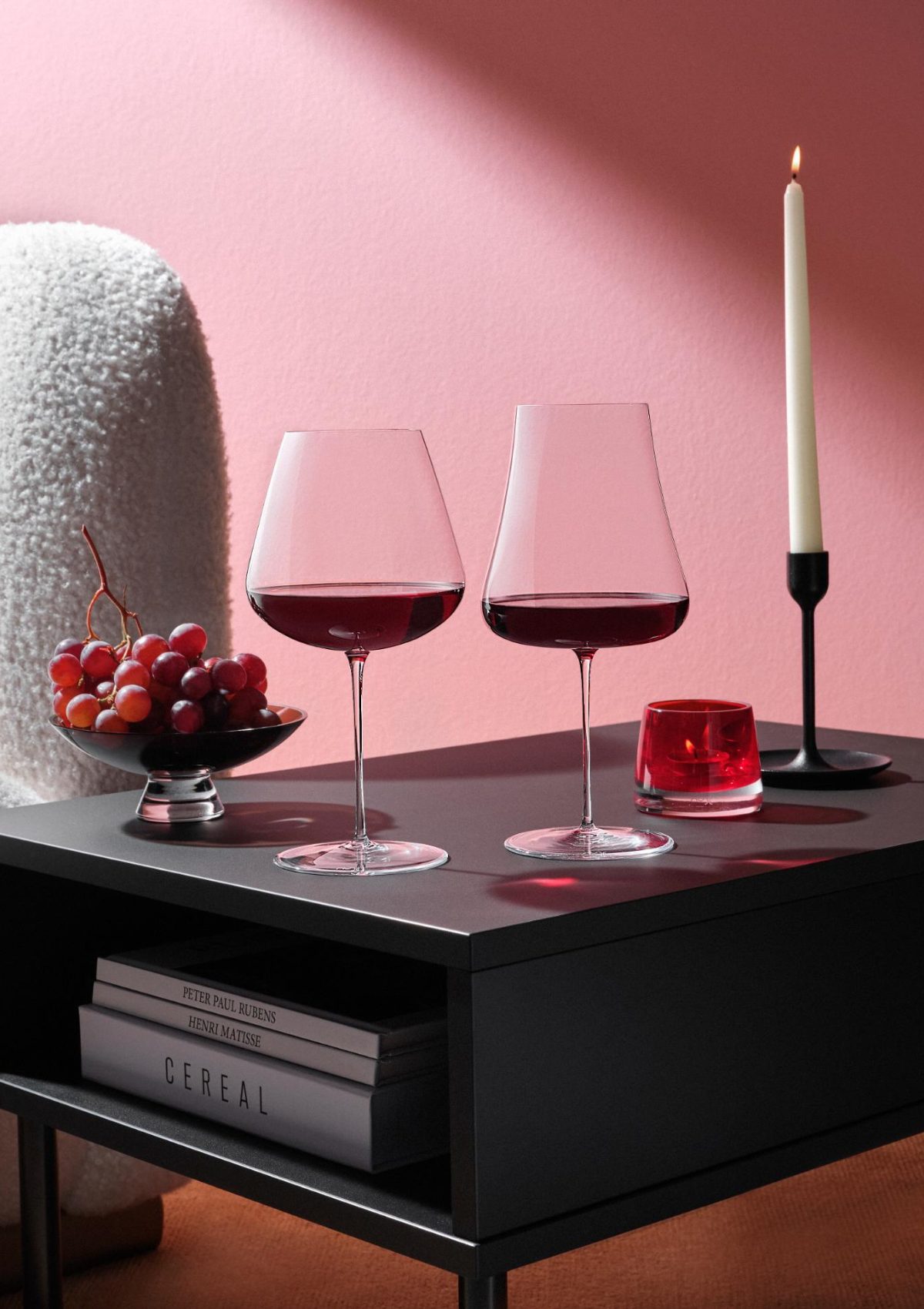 NUDE Stem Zero Volcano and Elegant red wine glasses on a dark coffee table with grapes, red votive and candle light