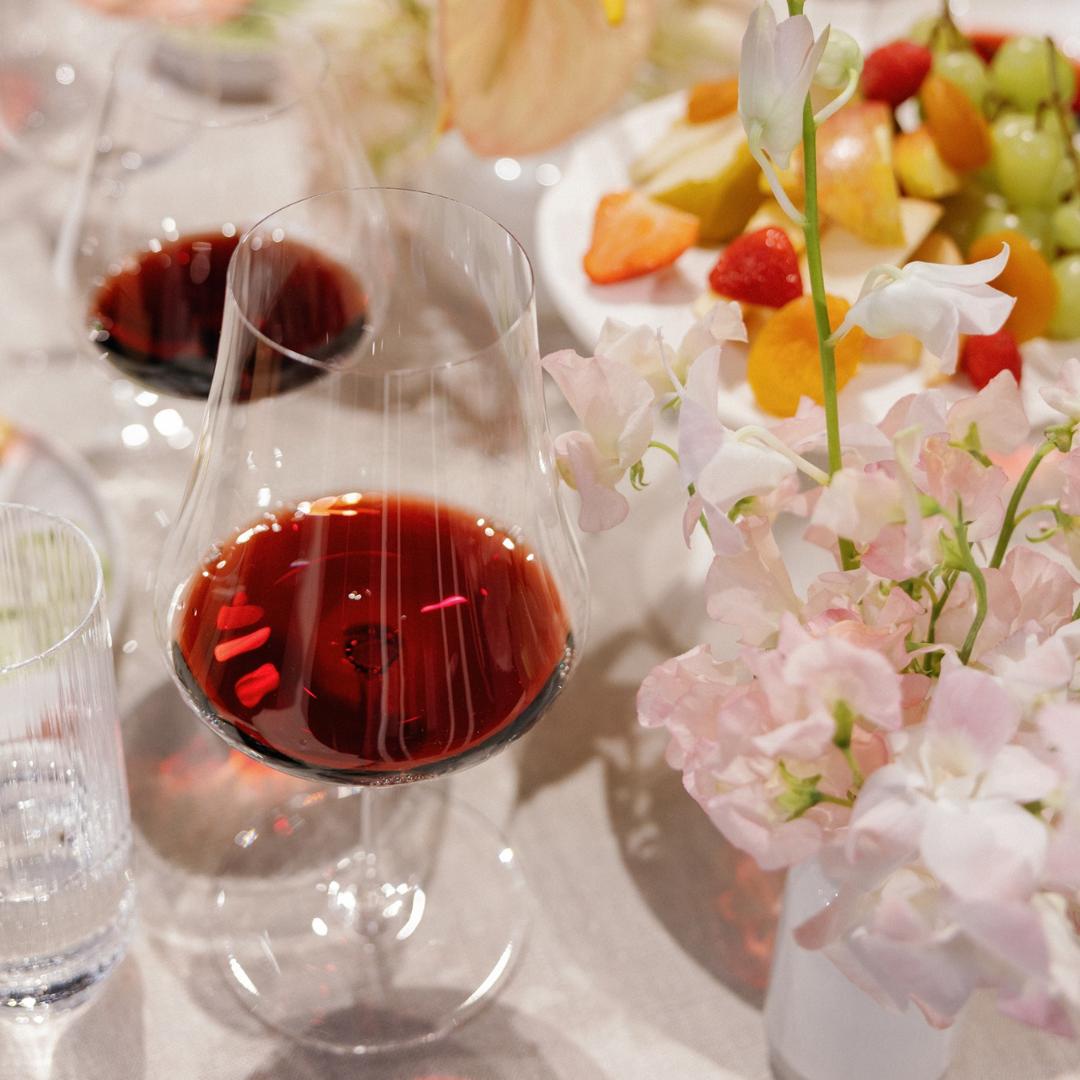 NUDE Stem Zero Volcano Red Wine Glass filled with red wine on a soft floral dinner table