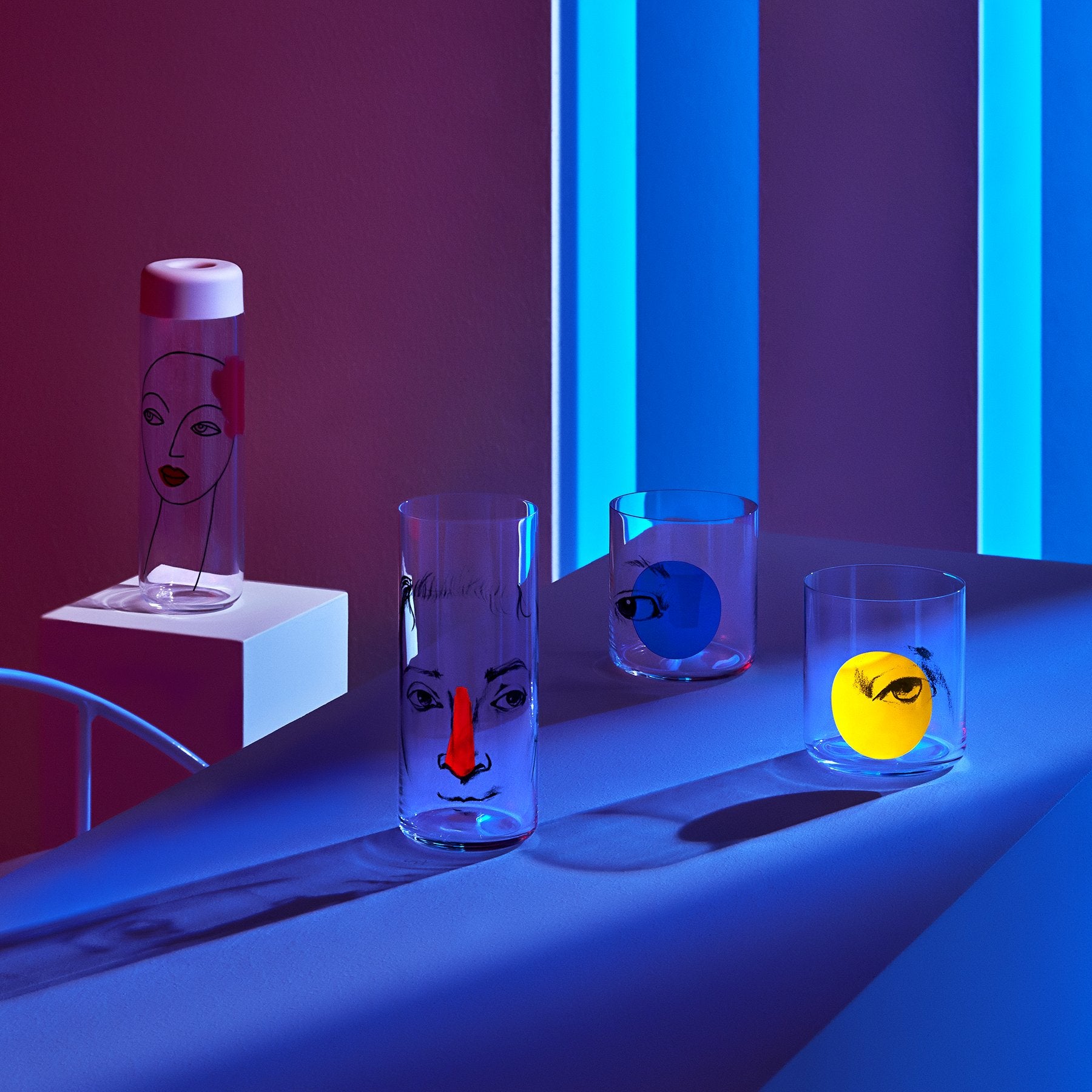 Lifestyle image of NUDE Rock &amp; Pop glass collection with jug, highball glass and whisky glass in light neon environment