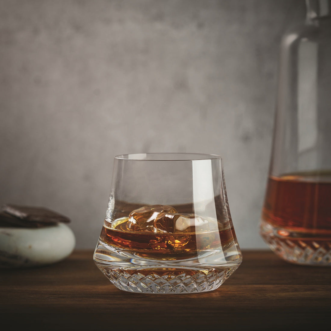 NUDE Paris whisky glass DOF, presented filled with whisky on table with grey background