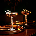 NUDE Big Top Coupe glass with linear patterned stem with elegant cocktail presented on a bar