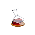 Wine decanter with red wine on a wooden coaster against a white background
