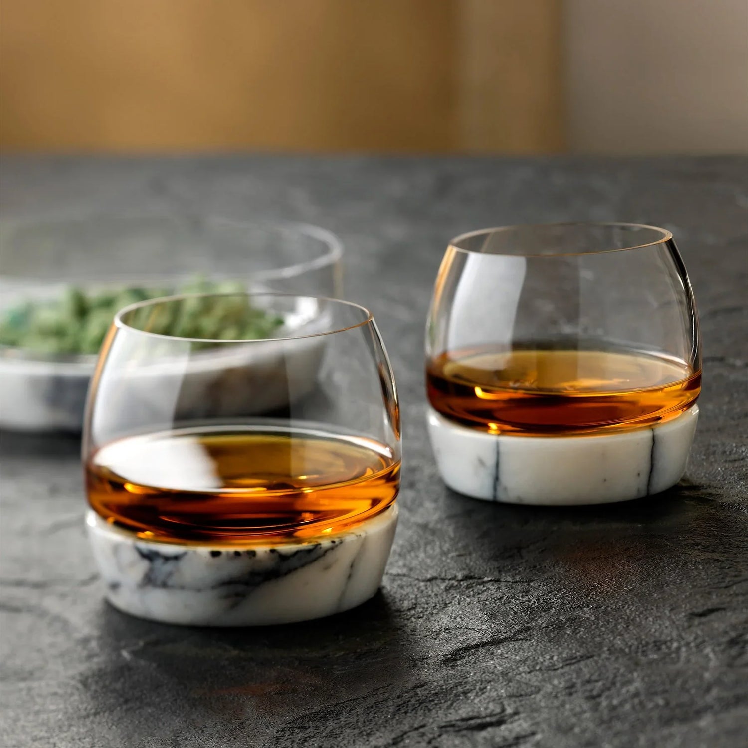An L-sized clear crystalline bowl with a marble base, containing green beads, designed for serving drinks or as a decorative piece.